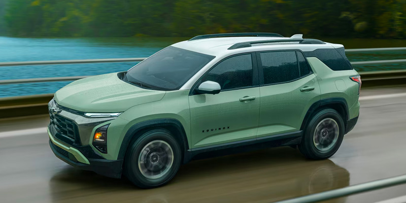 2026 Chevrolet Equinox driving on a wet road near a body of water
