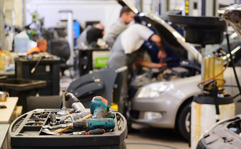 Auto repair technicians working in a service center with tools in the foreground.
